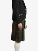 Person wearing a black blazer and green plaid kilt on a white background