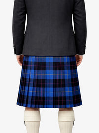 Person wearing a black jacket and blue plaid kilt on a white background