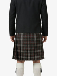 Person wearing a black jacket and plaid kilt on a white background