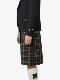 Person wearing a black jacket and plaid kilt on a white background