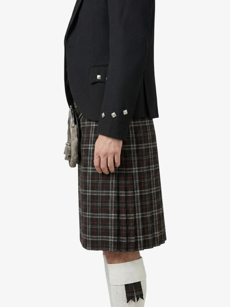 Person wearing a black jacket and plaid kilt on a white background