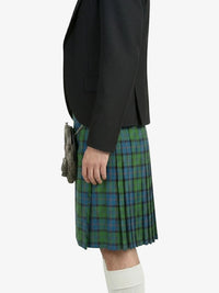 Person wearing a black jacket and green plaid kilt on a white background