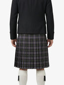 Person wearing a black blazer and plaid kilt on a white background