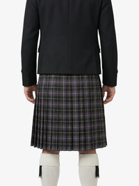 Person wearing a black blazer and plaid kilt on a white background