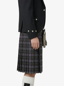 Person wearing a black jacket and plaid kilt on a white background