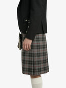 Person wearing a black blazer and plaid kilt on a white background