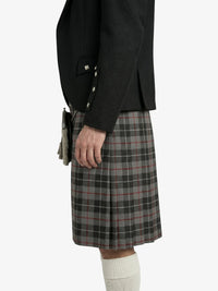 Person wearing a black blazer and plaid kilt on a white background