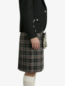 Person wearing a black blazer and plaid kilt on a white background