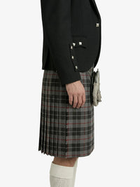 Person wearing a black blazer and plaid kilt on a white background
