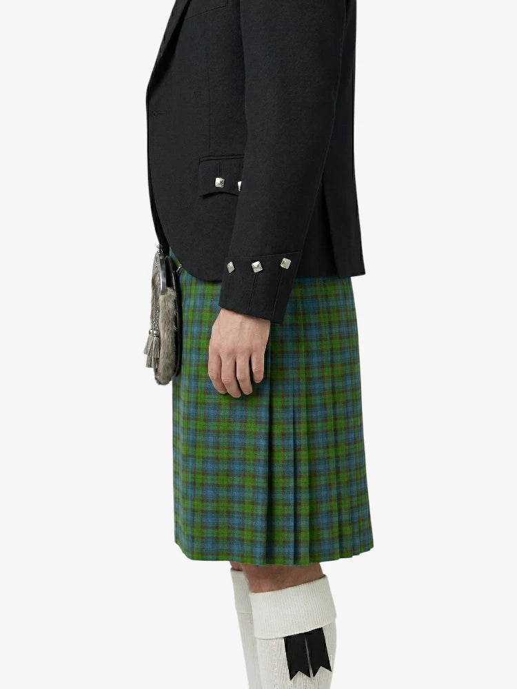 Person wearing a black blazer and green plaid kilt on a white background
