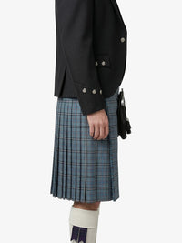 Person wearing a black blazer and plaid kilt on a white background