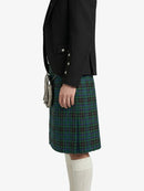 Person wearing a black jacket and green plaid kilt on a white background