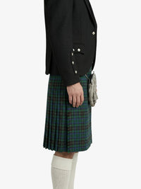 Person wearing a black blazer and plaid kilt on a white background
