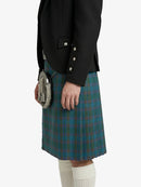Person wearing a black jacket and green plaid kilt on a white background