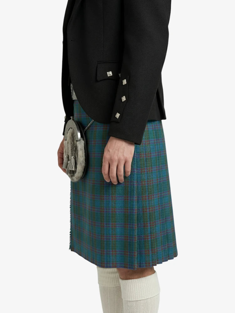 Person wearing a black jacket and green plaid kilt on a white background