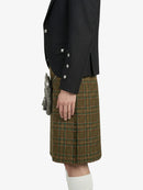 Person wearing a black jacket and green plaid kilt on a white background