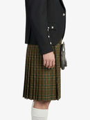 Person wearing a black jacket and green plaid kilt on a white background