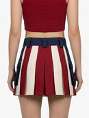 Person wearing a red top and a pleated skirt with red, white, and blue stripes on a white background